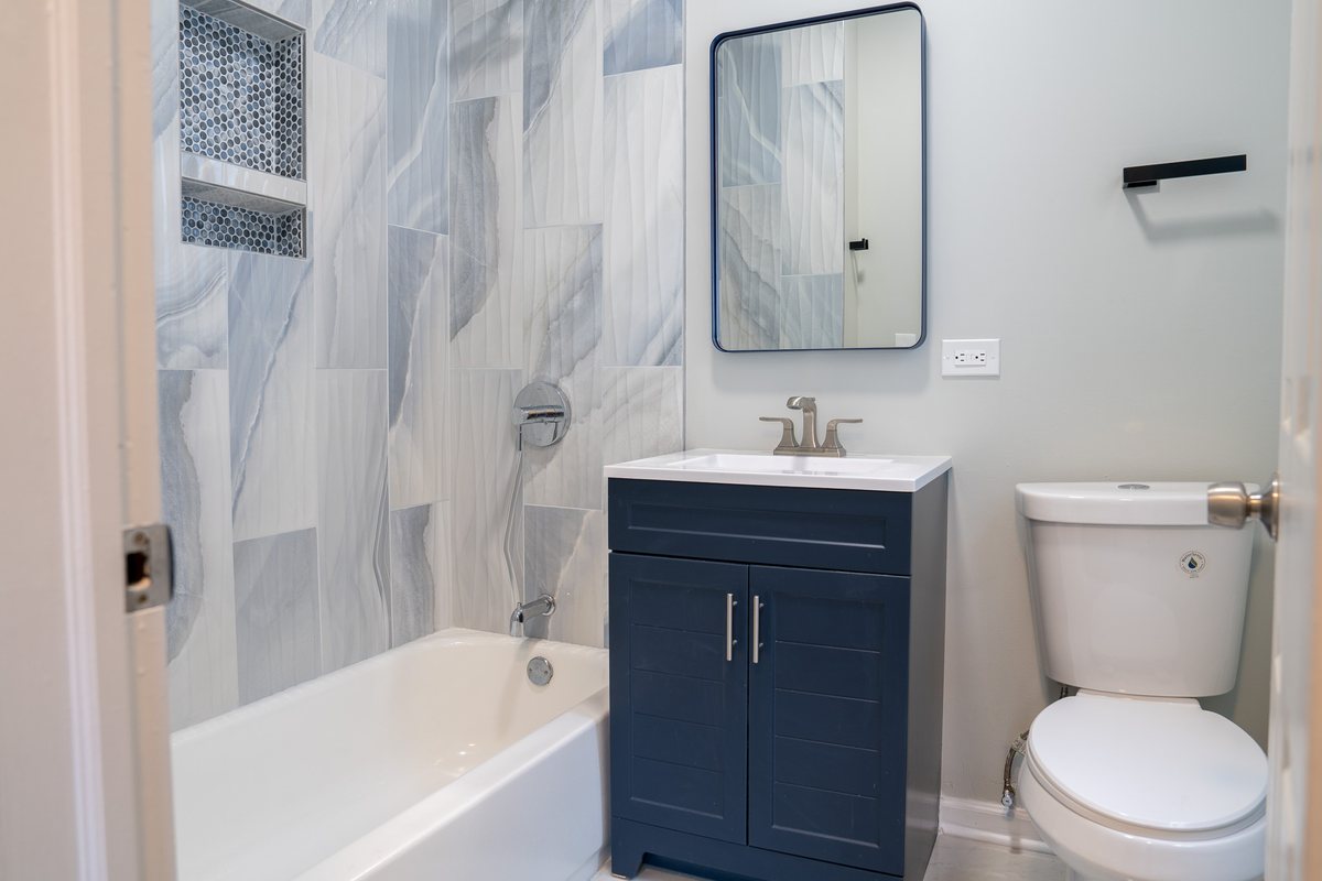 Bathroom with tiled tub surround and navy vanity